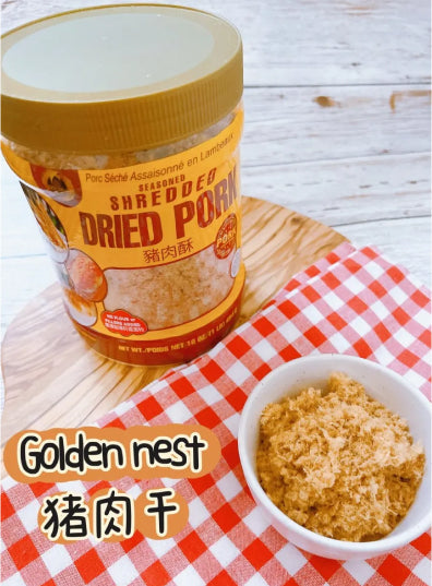 A container of "Seasoned Shredded Dried Pork" sits on a wooden surface beside a small white bowl filled with the product. A red-checkered cloth adds contrast. Text reads "Golden Nest."