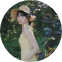 一位身穿黃色連衣裙、頭戴草帽的女士站在綠意盎然的背景中。柔和的燈光和大地色調營造出寧靜的夏日氣息。
